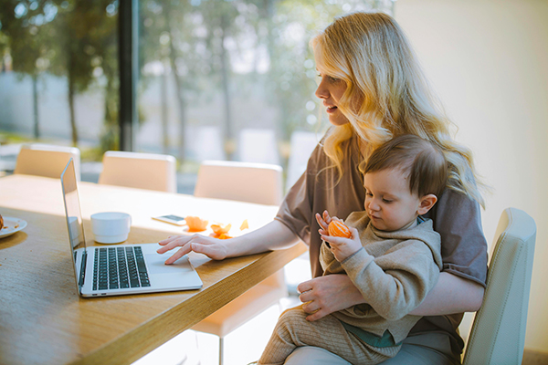 Woman working on laptop with her child